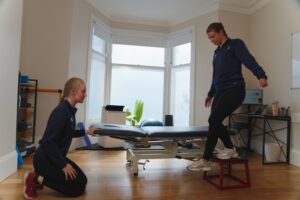 Physiotherapist with patient performing a knee exercise.